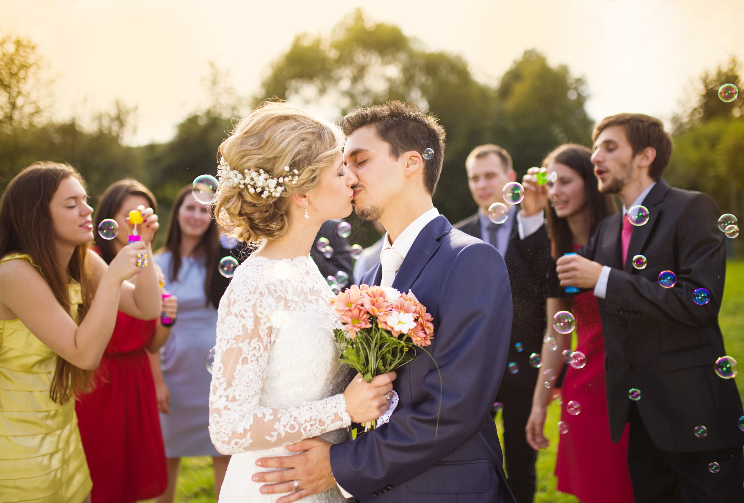 Young newlyweds kissing and enjoying romantic moment together at wedding reception outside